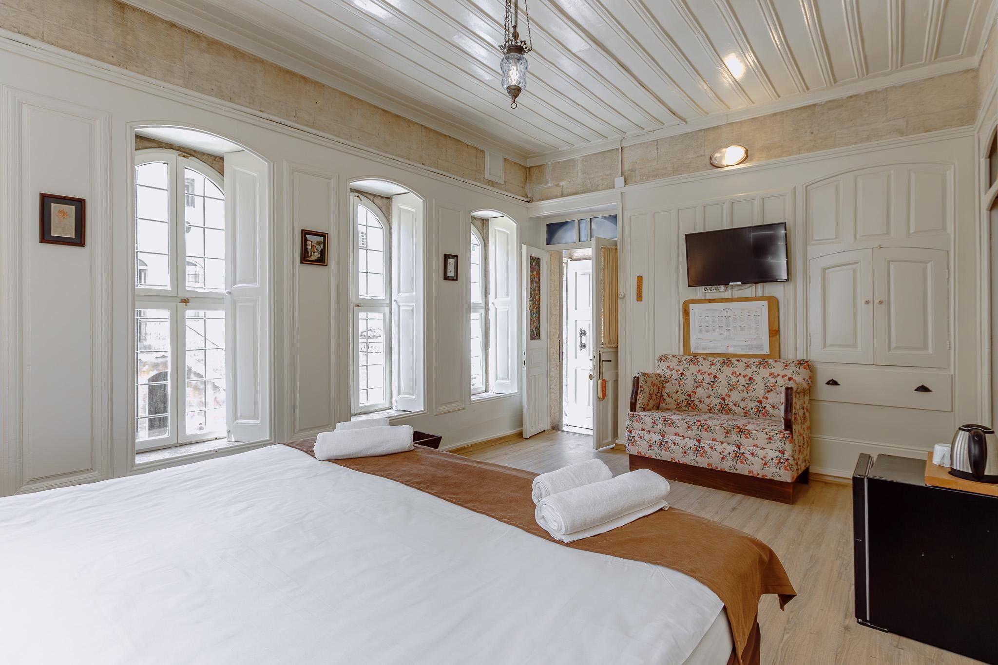 A spacious hotel room with a large bed, a sofa, and a television.