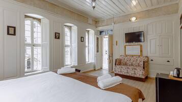 A spacious hotel room with a large bed, a sofa, and a television.