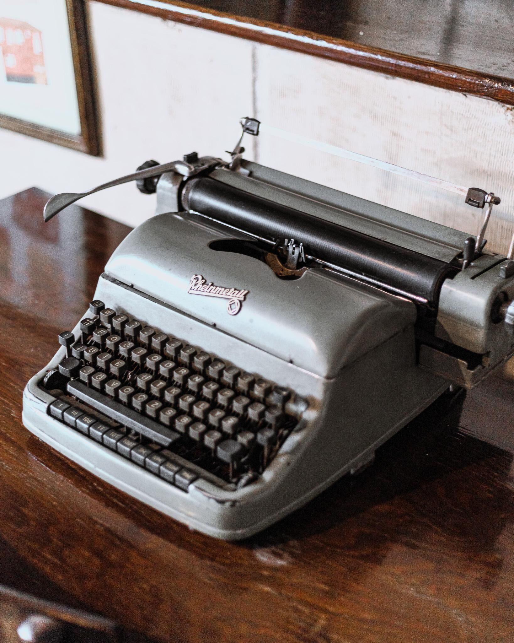 Une machine à écrire ancienne, dotée d’un boîtier en métal et de touches noires, posée sur une surface en bois.