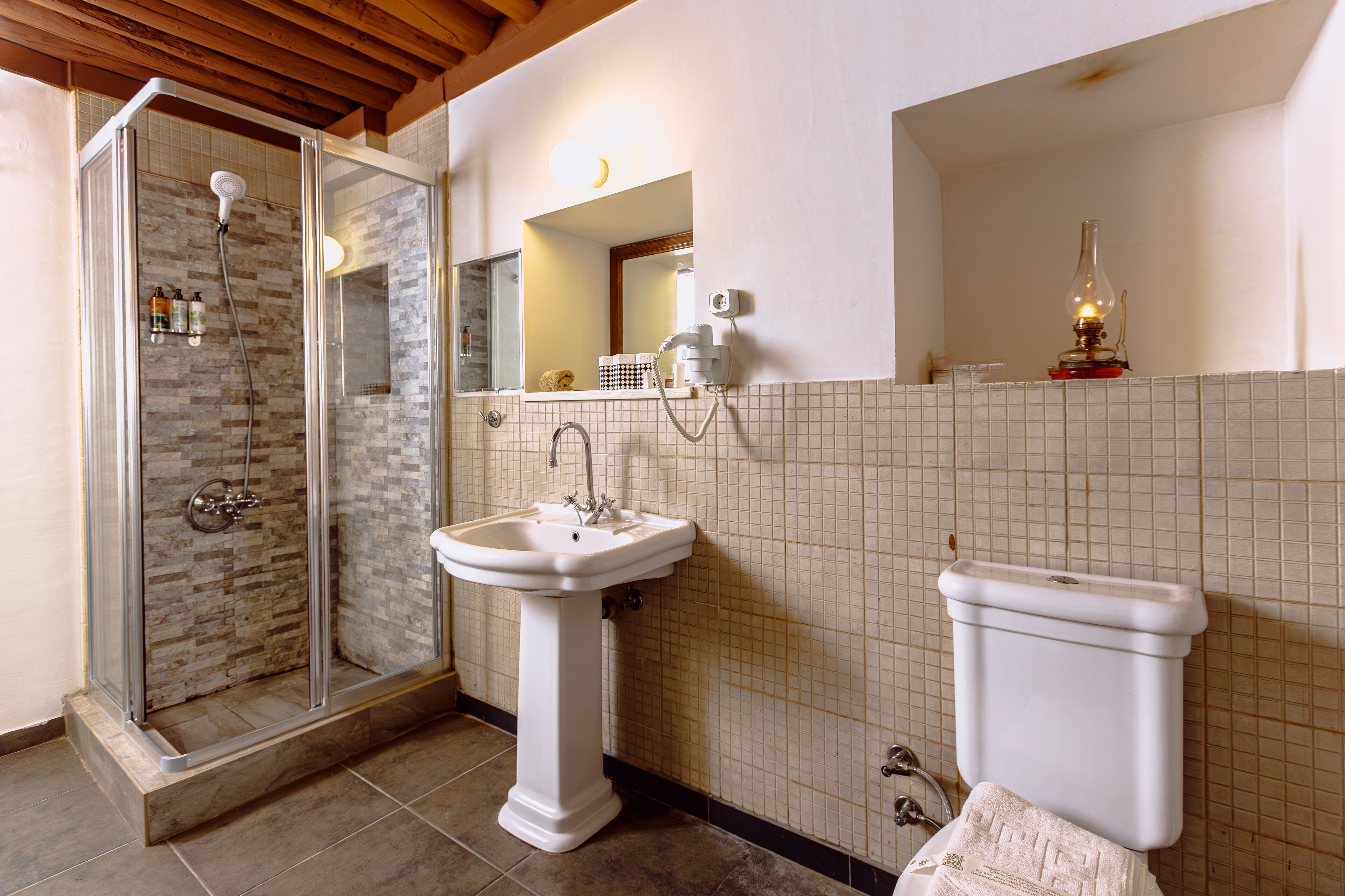 Une salle de bain avec une douche à parois de verre, un lavabo sur colonne et des toilettes.