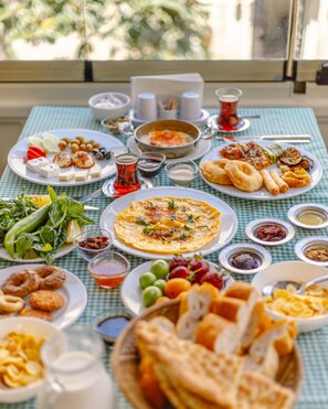 A table set with various dishes including a large omelette, vegetables, and bread, suggesting a meal setup. - Anadolu Evleri (Gaziantep)
