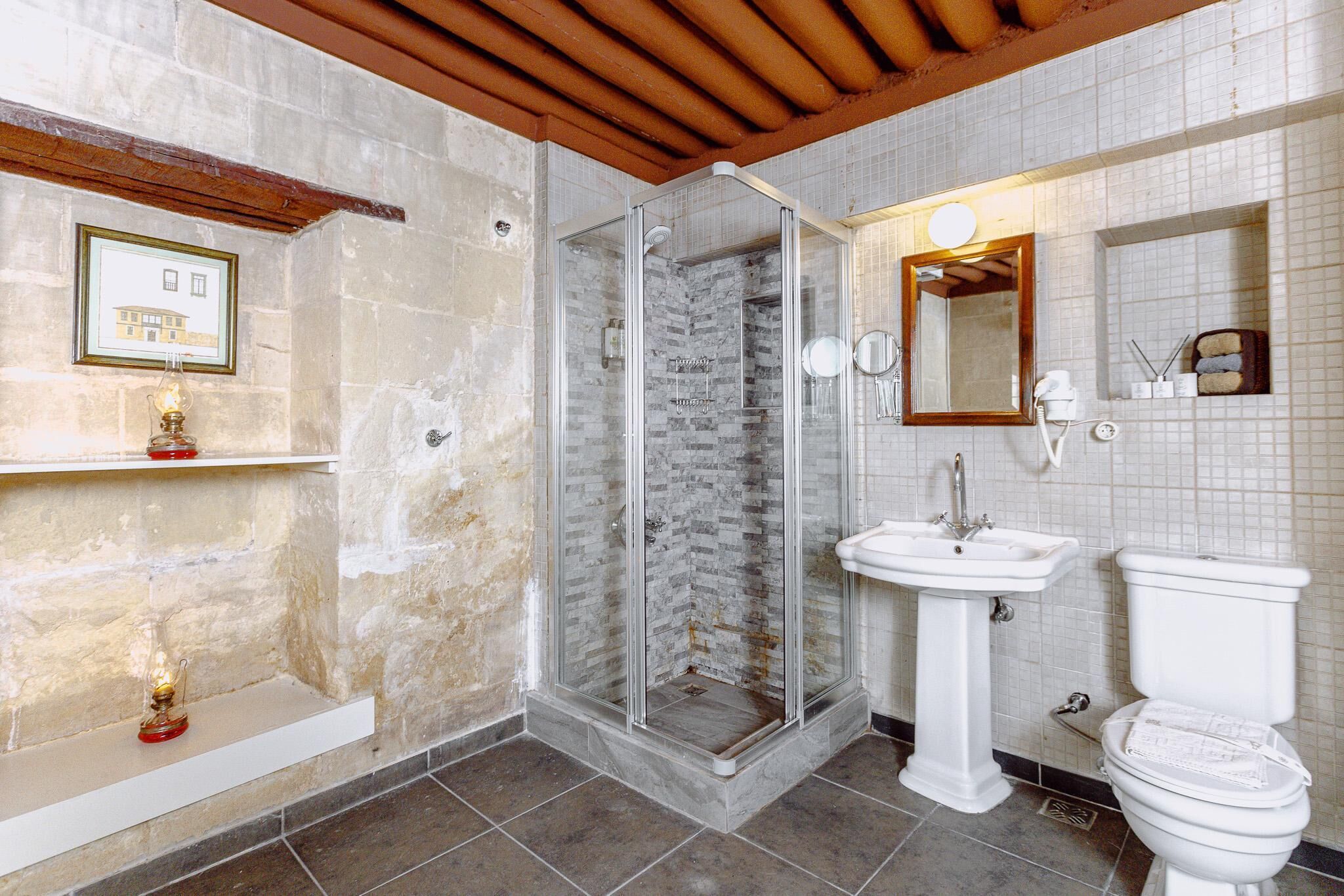 A bathroom with a glass-enclosed shower, a white pedestal sink, and a toilet.