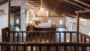 Un dormitorio rústico con techo de madera, lámpara colgante y cama con almohadas.