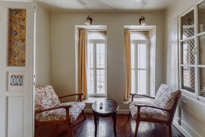 A room with two chairs, a small table, and a window with curtains. - Anadolu Evleri (Gaziantep)