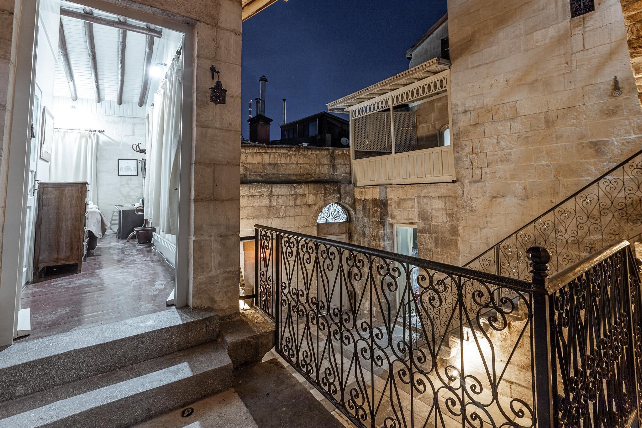 Un escalier en pierre, agrémenté de rampes en métal ouvragé, mène à un balcon.