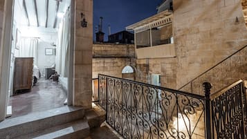 Un escalier en pierre, agrémenté de rampes en métal ouvragé, mène à un balcon.