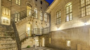 Un edificio histórico con un patio central, una escalera de piedra y múltiples ventanas.