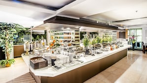 Een moderne buffetopstelling met diverse food stations, een overzichtelijke en ruime indeling, en decoratieve planten.