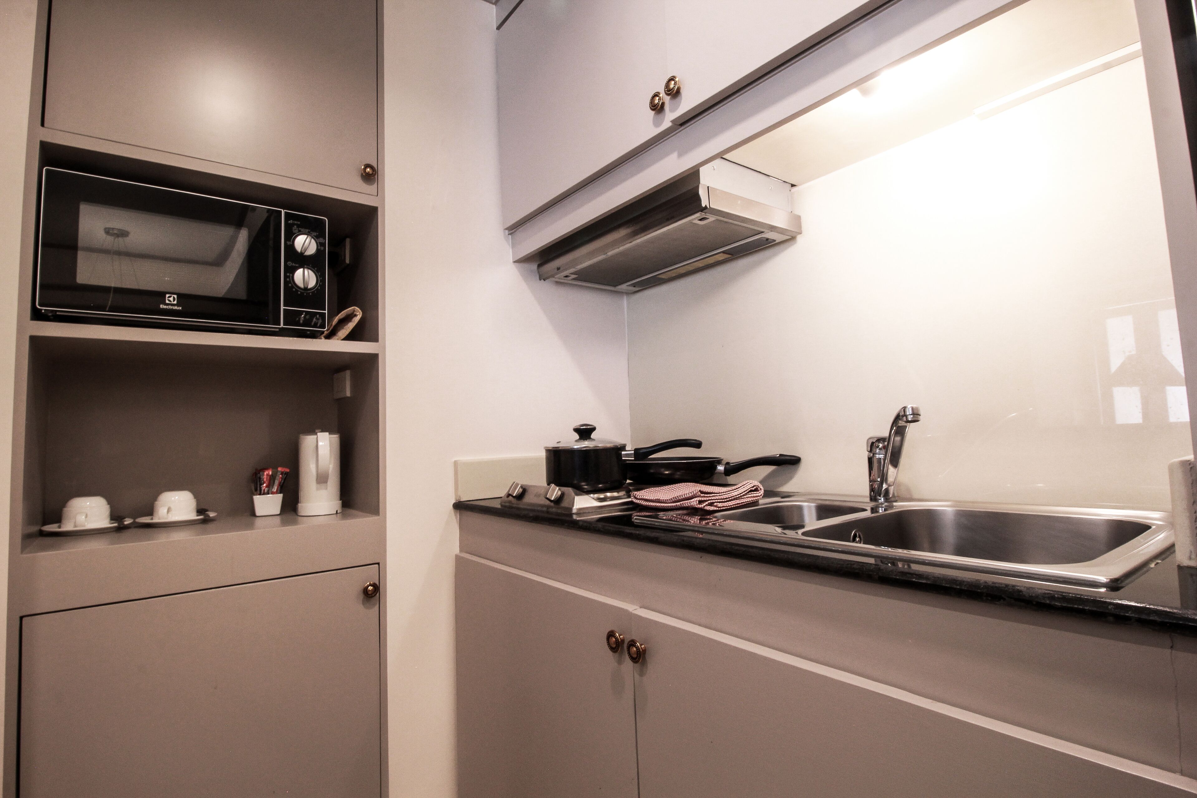 A compact kitchen with a microwave, stove, sink, and cabinets.