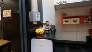 A kitchen area with a Cuckoo refrigerator, a coffee machine, and a shelf with various items. - Just4U (Seoul)
