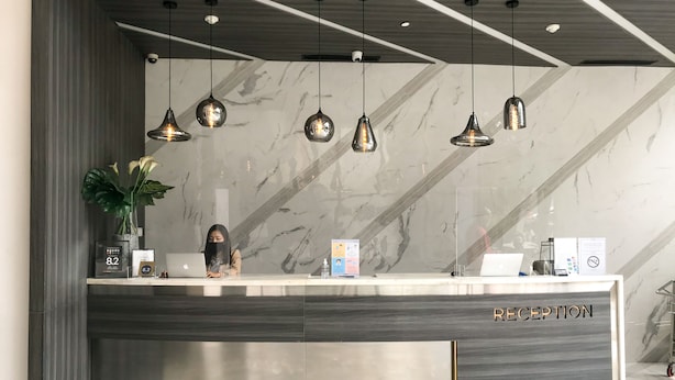 A reception desk with a marble wall, a potted plant, and a laptop. - Juno Tanah Abang Jakarta (Jakarta)