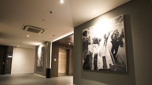 A hallway with a large black and white photograph on the wall, a door with a sign, and a vent on the ceiling. - Juno Tanah Abang Jakarta (Jakarta)