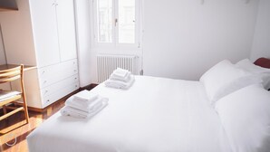 A hotel room with a bed, a wooden chair, a radiator, and a window. - Italianway   - Giulio Romano (Milan)