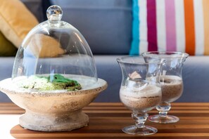 A dessert display with a glass dome and two glasses on a wooden table. - Villa Vollard (Malevizi)