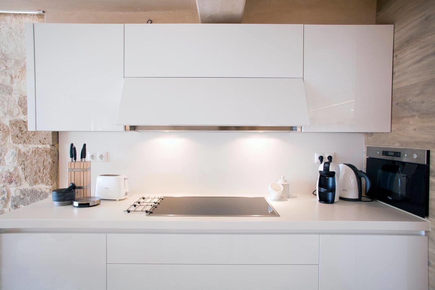 A modern kitchen with white cabinetry, a stainless steel sink, and a built-in oven.