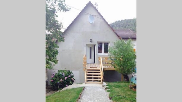 A small, single-story house with a wooden staircase leading to a door.
