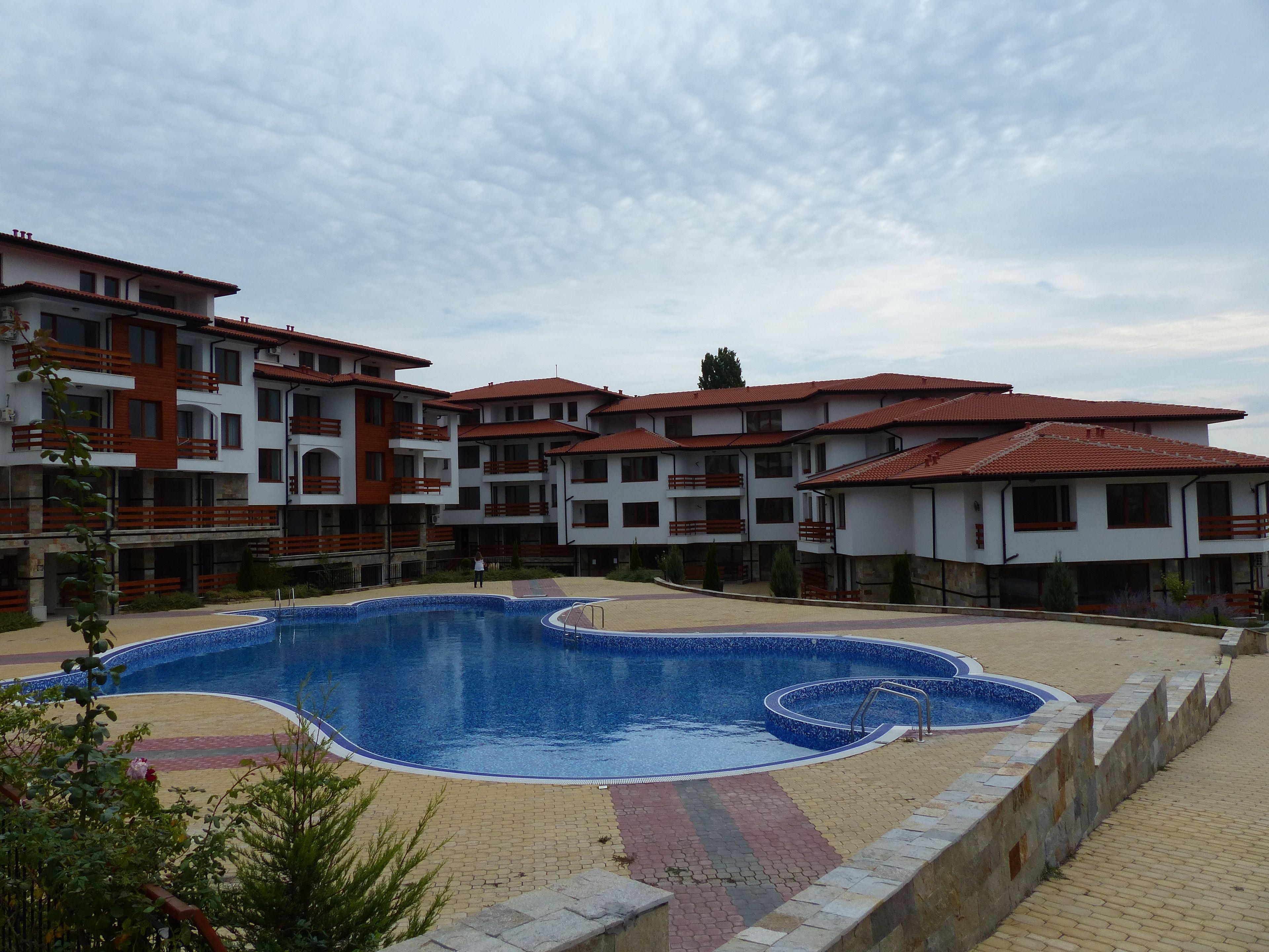 A swimming pool with a unique design, surrounded by multi-story buildings with balconies.