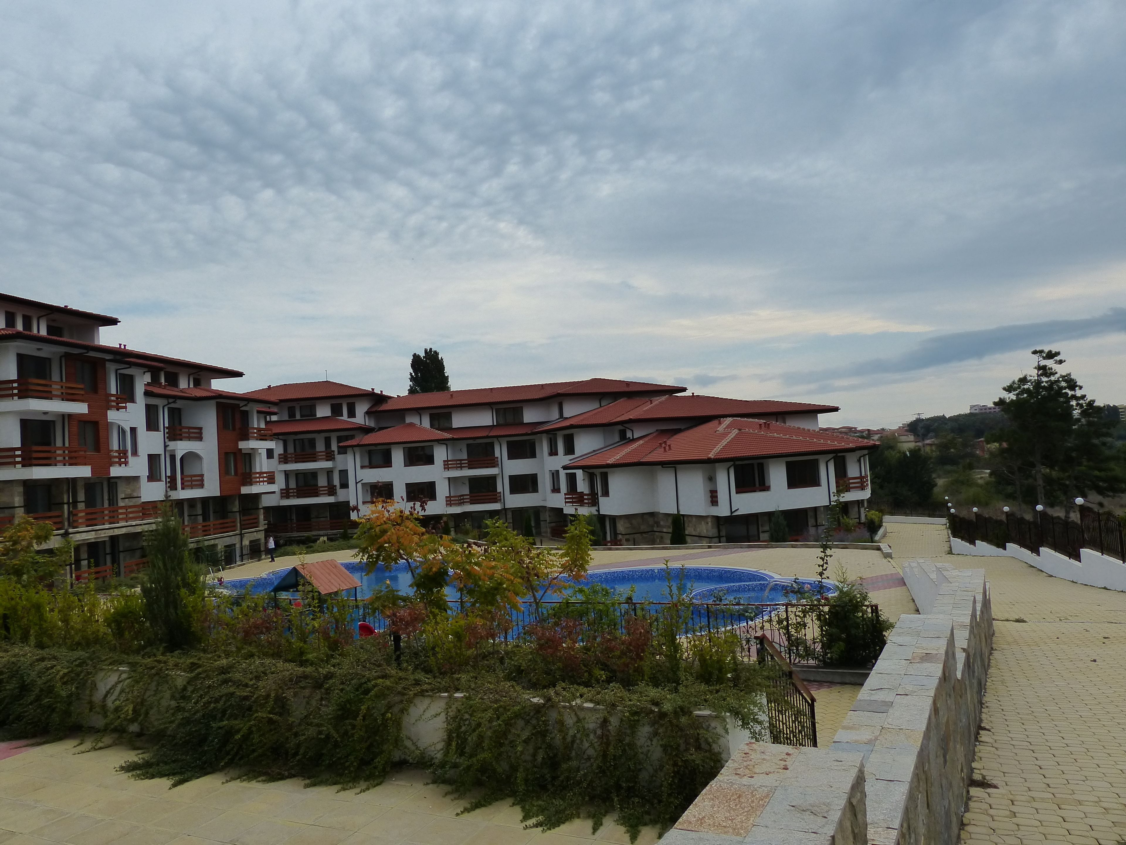 Un hotel de varios pisos con balcones, piscina y jardín ajardinado.