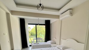 A hotel room with a large bed, two bedside tables, a ceiling light fixture, and a view of the outdoors. - Cilek Butik Otel (Cesme)
