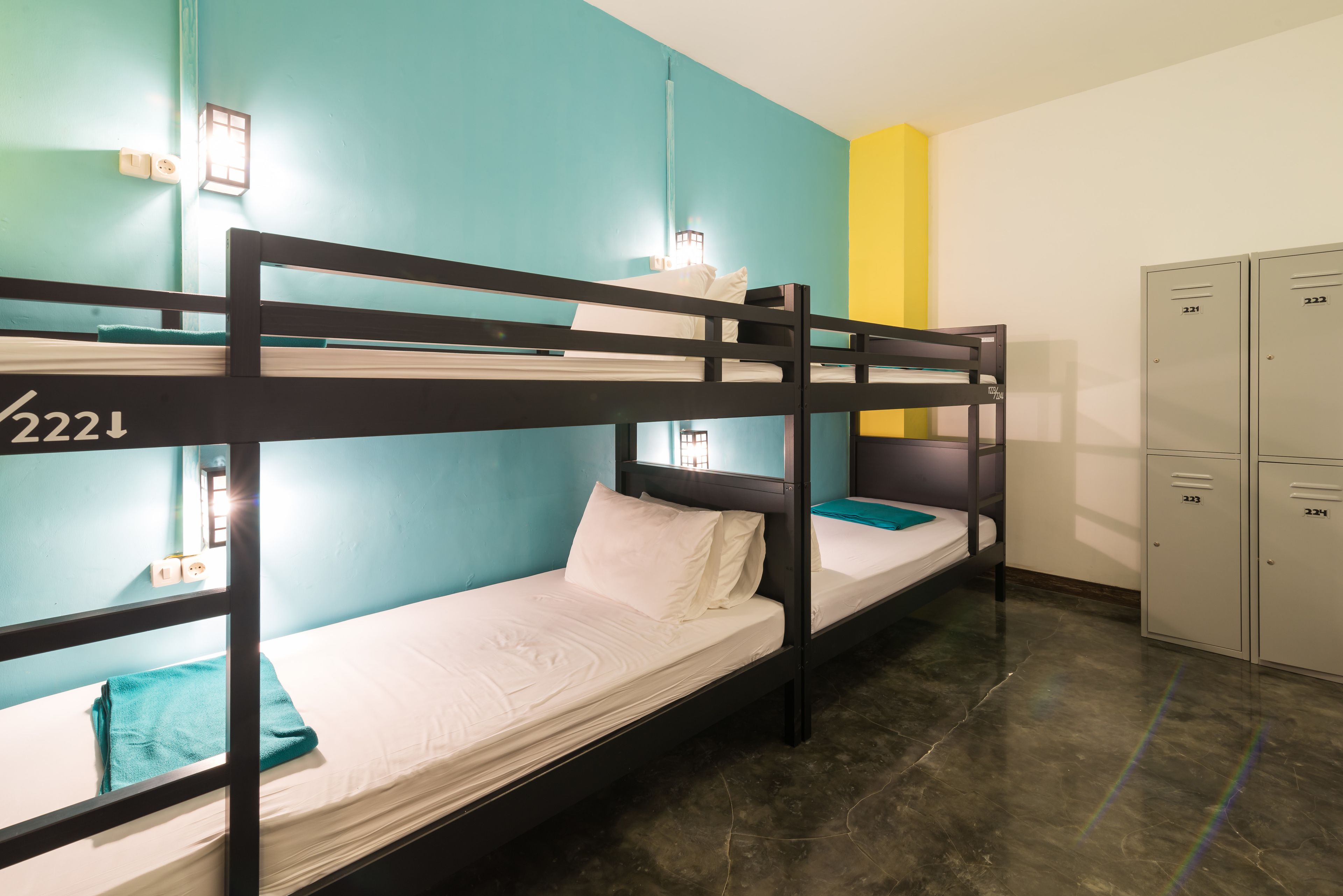 A bunk bed room with a blue wall, a yellow accent wall, and a metal locker area.