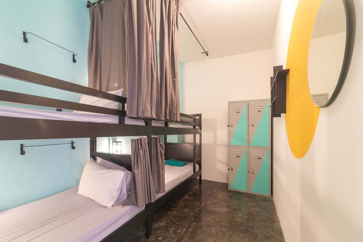 Habitación con literas, un espejo, un armario y la puerta del baño.