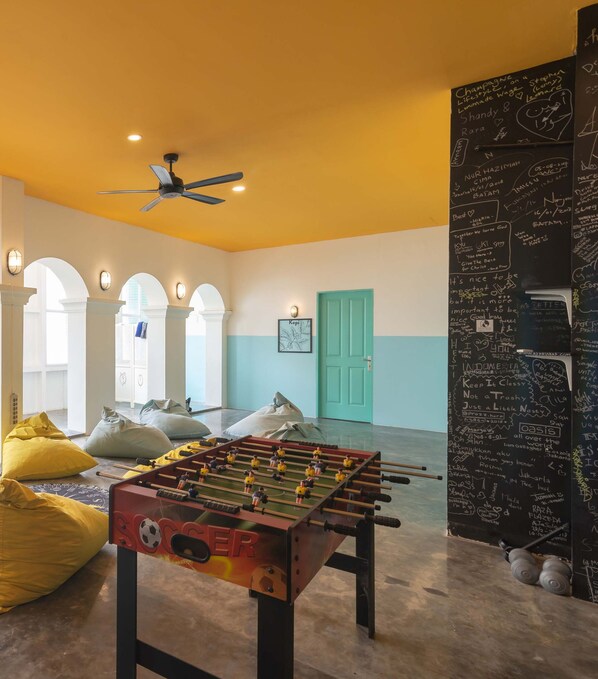 A room with a foosball table, bean bags, and a chalkboard with writings. - Wonderloft Hostel Kota Tua (Jakarta)