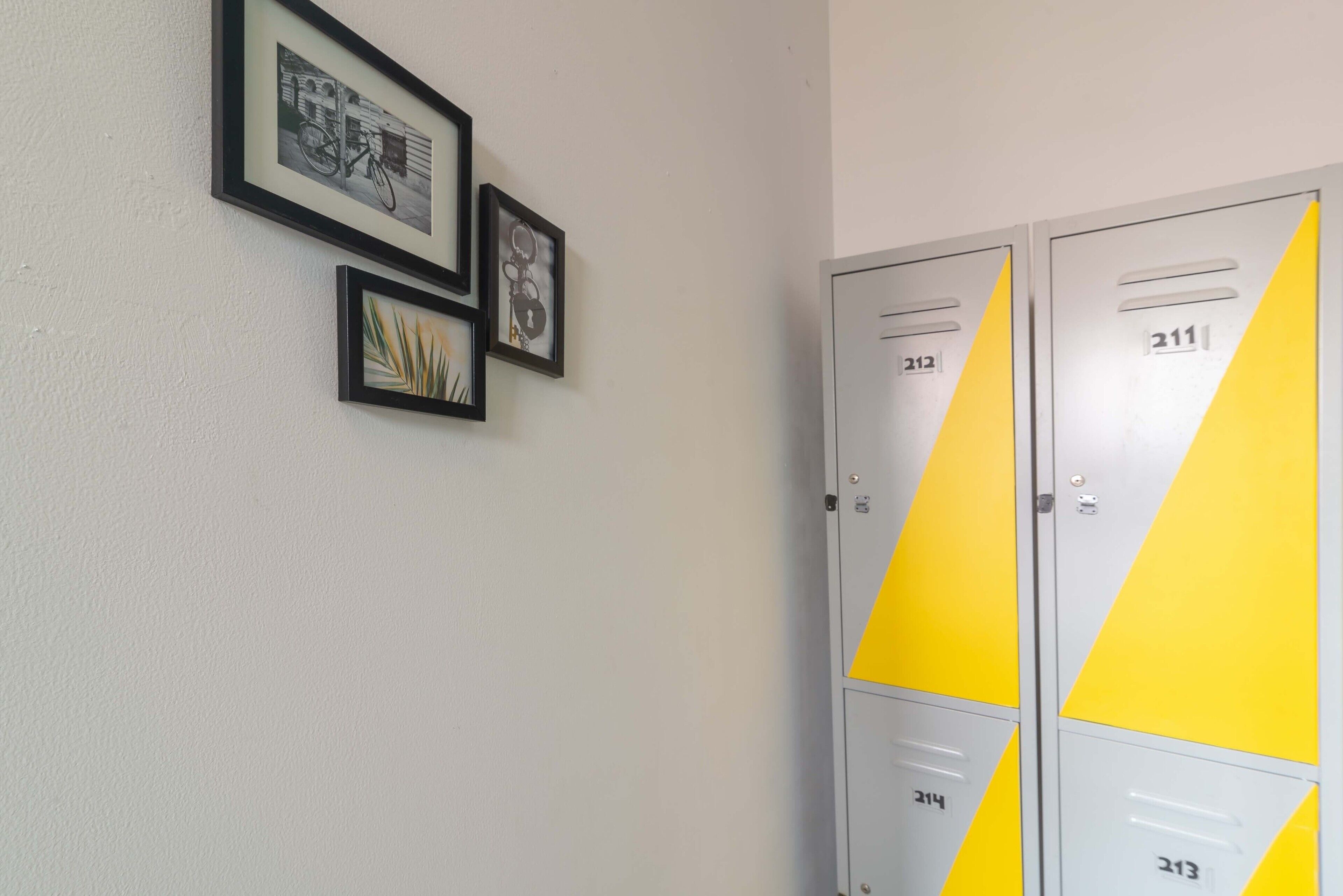 A hallway with lockers numbered 211 and 213, and framed pictures on the wall.