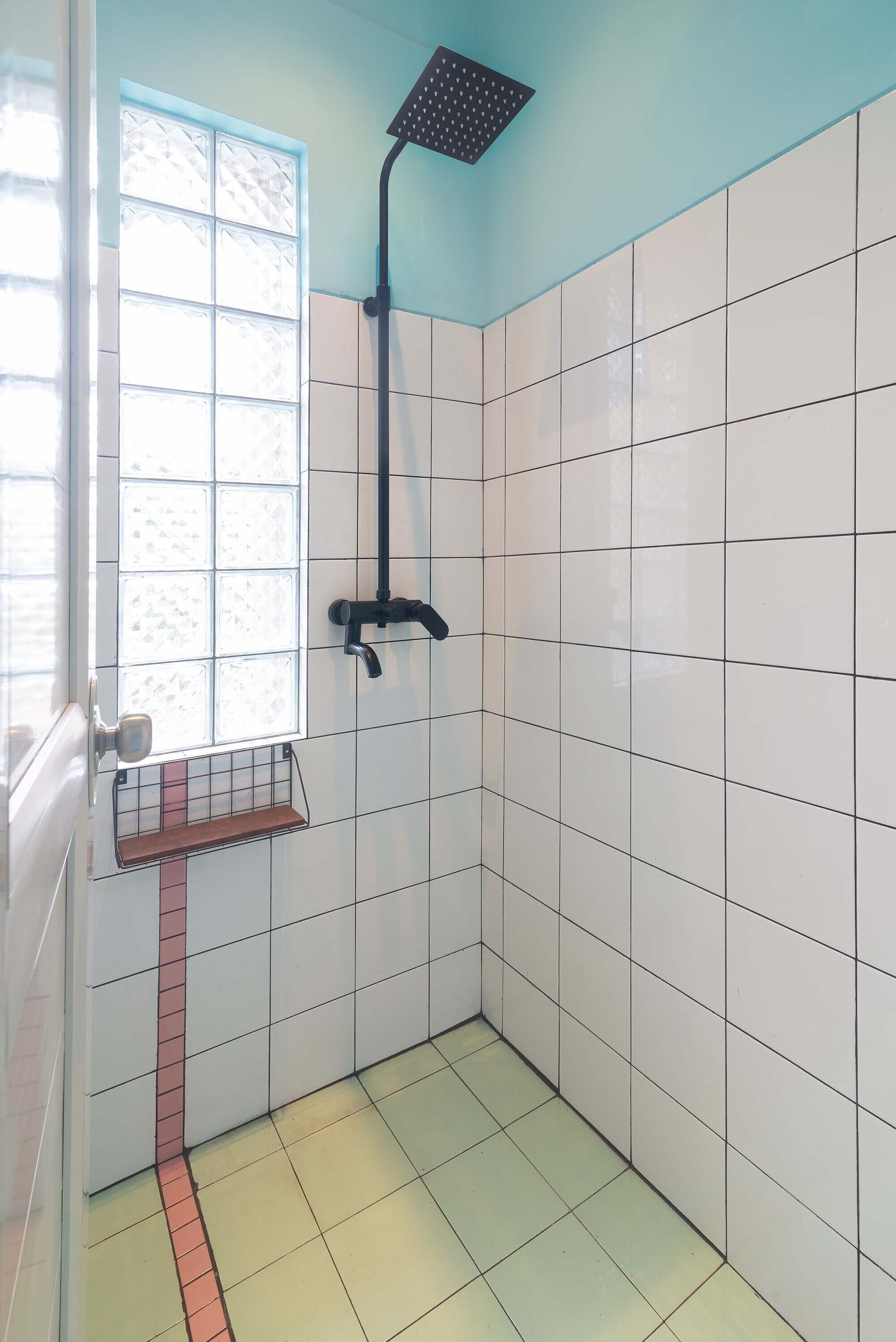 A small, tiled bathroom with a shower, a window, and a towel rack.