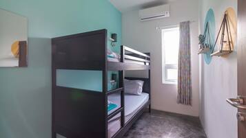 A bunk bed room with a window, air conditioning unit, and a curtain.