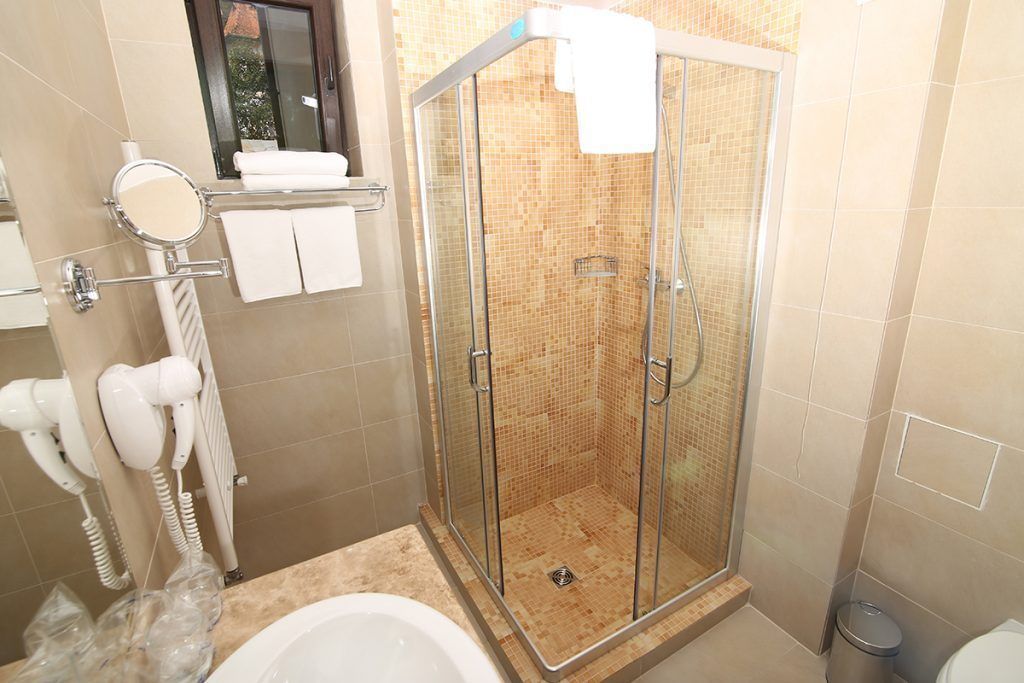 A shower with a glass door, a white bathtub, and a towel rack with towels.