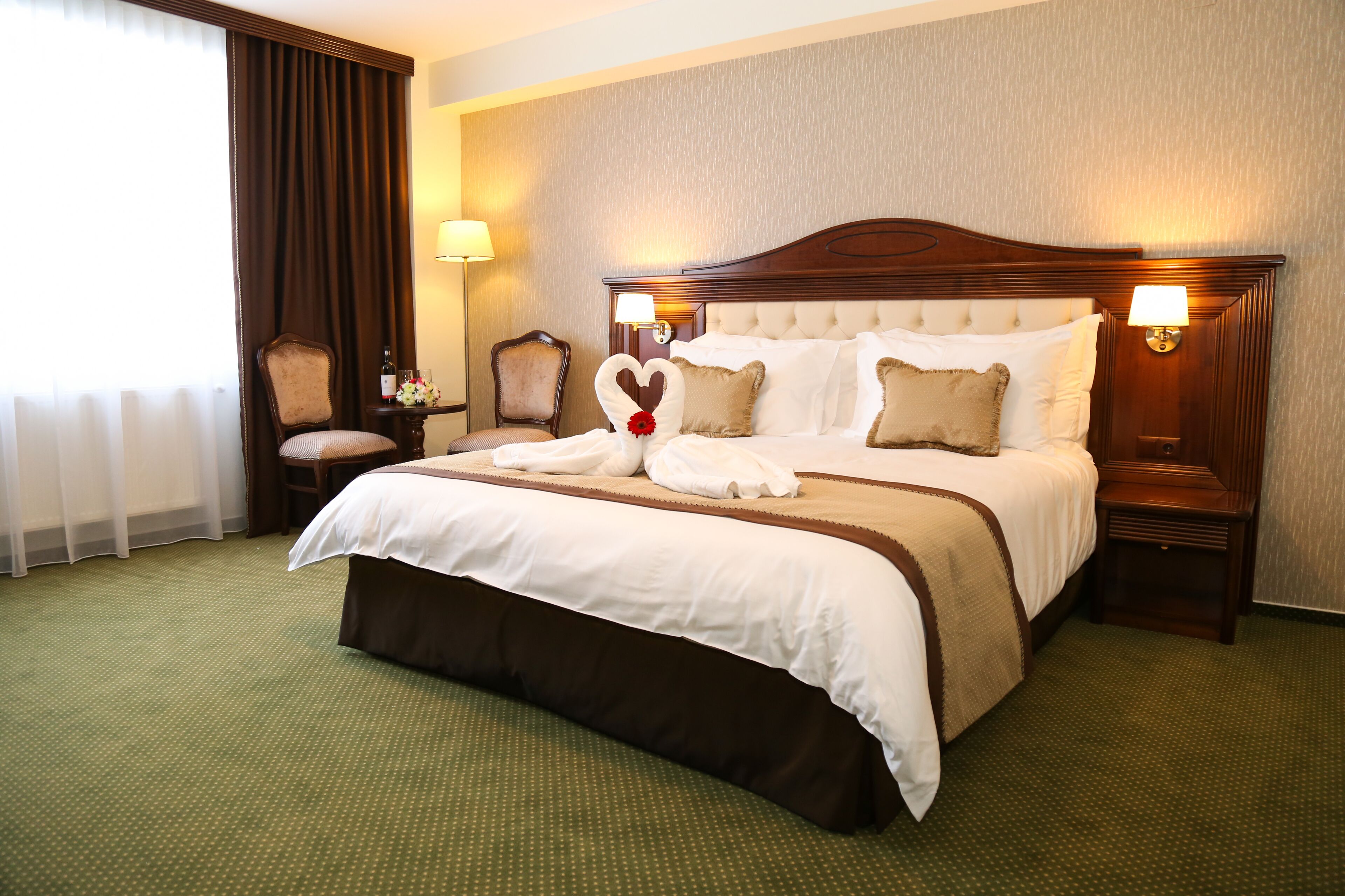 A hotel room with a large bed, two bedside tables, a chair, and a lamp.