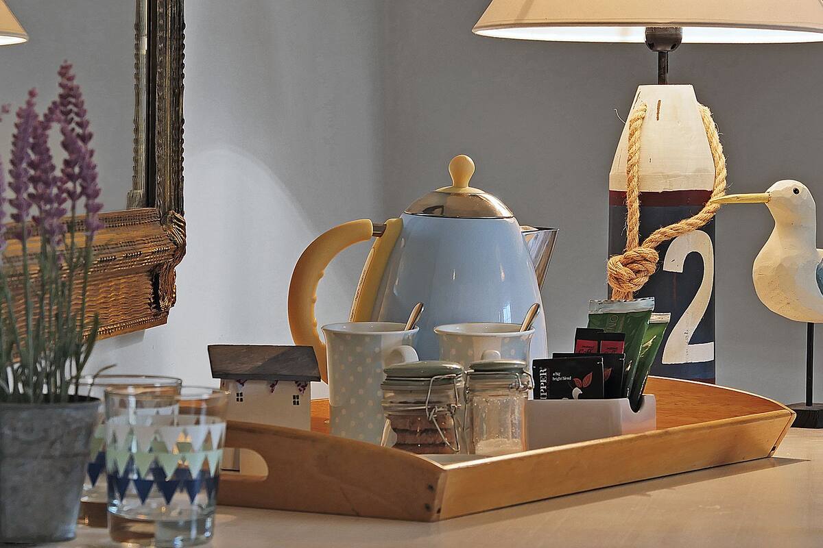 A wooden tray with kitchenware, a lamp, and decorative items on a table.