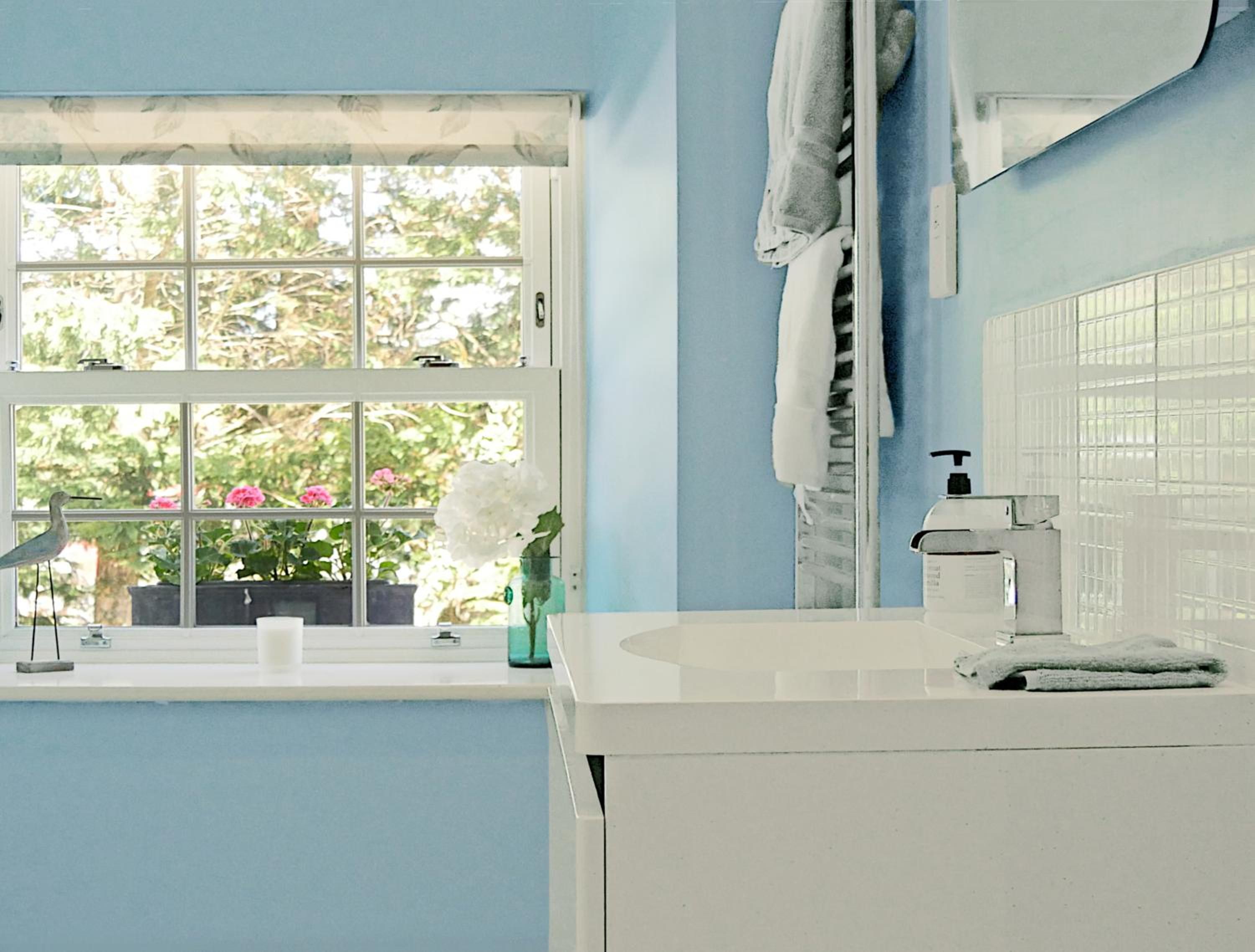 A bathroom with a window, a sink, and a towel rack.
