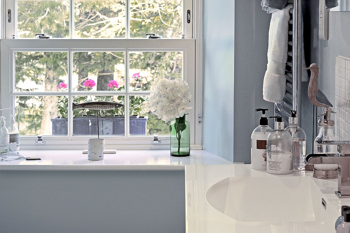 A bathroom with a large window, a sink, and toiletries.