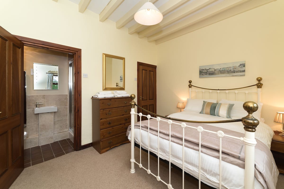 A bedroom with a bed, dresser, mirror, and a painting on the wall.