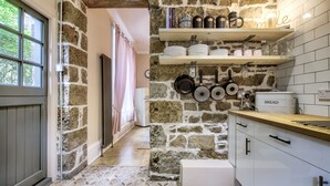 A kitchen with stone walls, wooden shelves, and a tiled floor. - Maya's Glasgow Holiday Homes (Glasgow)