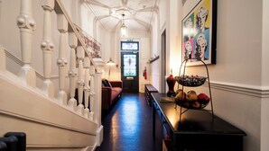 A hallway with a staircase, a chandelier, a framed artwork, and a fruit basket. - Maya's Glasgow Holiday Homes (Glasgow)