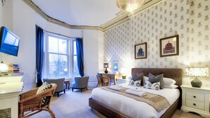 A bedroom with a large bed, a desk, a chair, and a television. - Maya's Glasgow Holiday Homes (Glasgow)