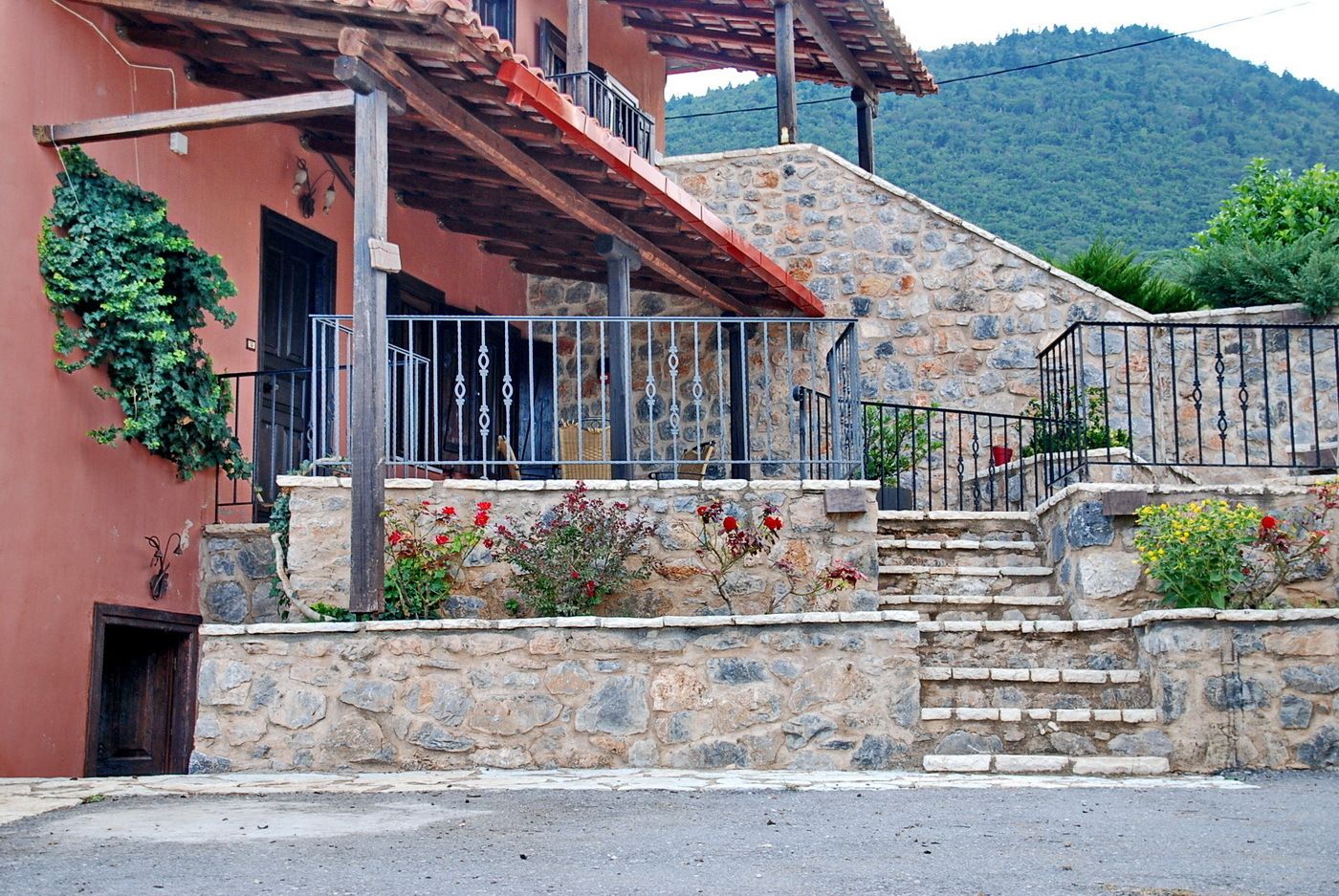 Una casa de piedra con un balcón de madera, una escalera de piedra y una barandilla de metal.