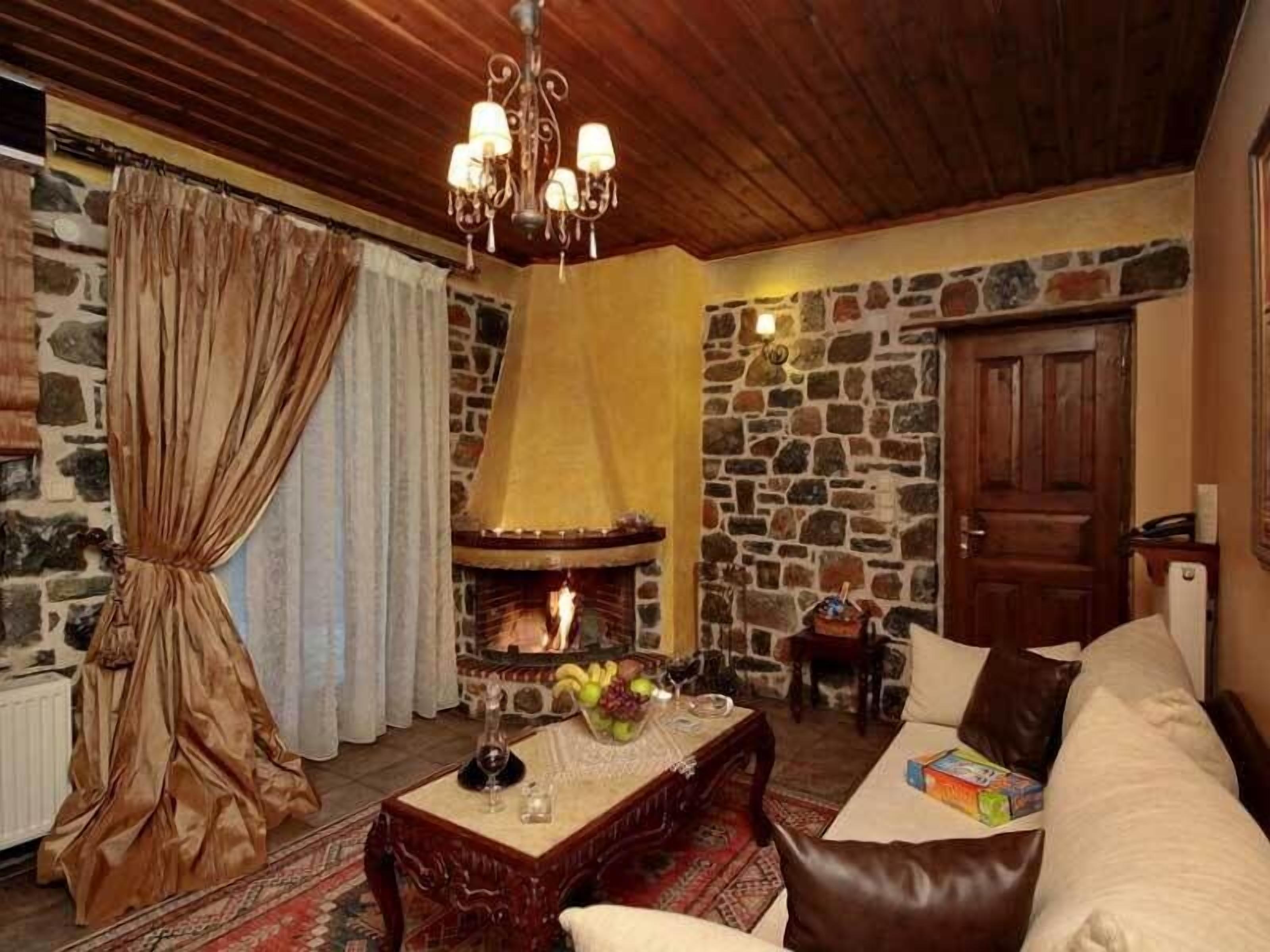 A cozy living room with a stone fireplace, wooden ceiling, and a sofa.