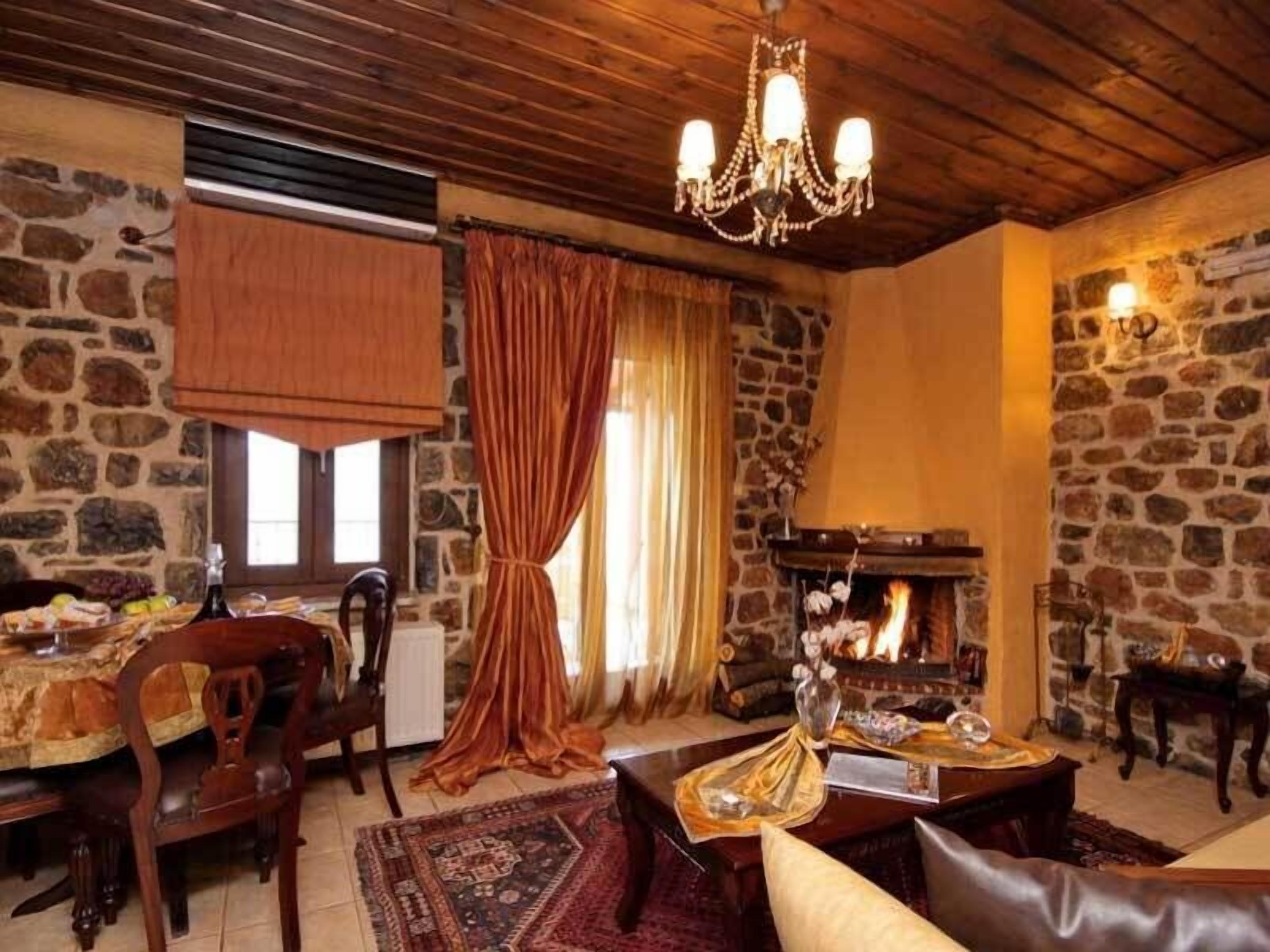 Un salón acogedor con pared de piedra, techo de madera, chimenea y candelabro.