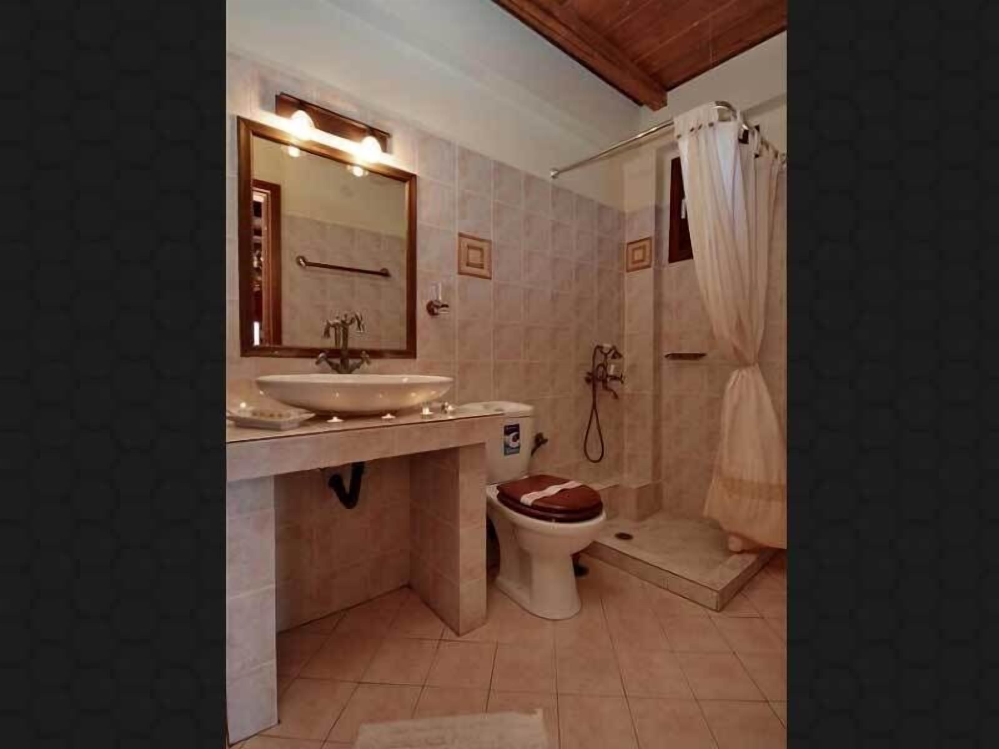 A bathroom with a sink, mirror, toilet, shower, and a towel rack.
