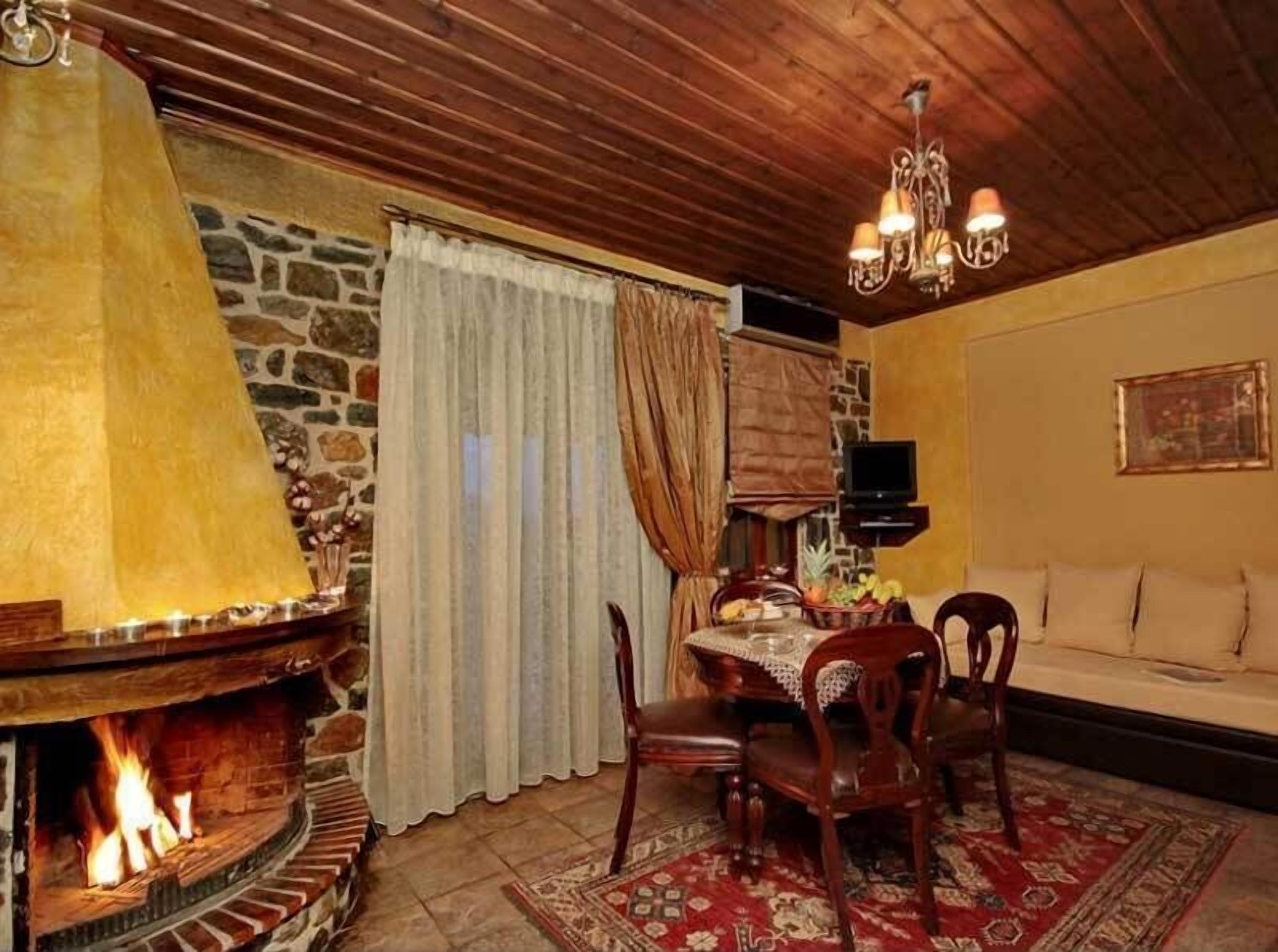 Ein gemütliches Wohnzimmer mit Kamin, Holzbalkendecke und einem Esstisch mit Stühlen.