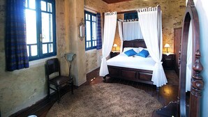 A bedroom with a four-poster bed, a chair, a small table, and a lamp. - Villa Sofas (Platanias)