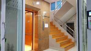 An elevator with a no smoking sign, a staircase with wooden steps, and a glass door. - The Best Place (Samut Prakan)
