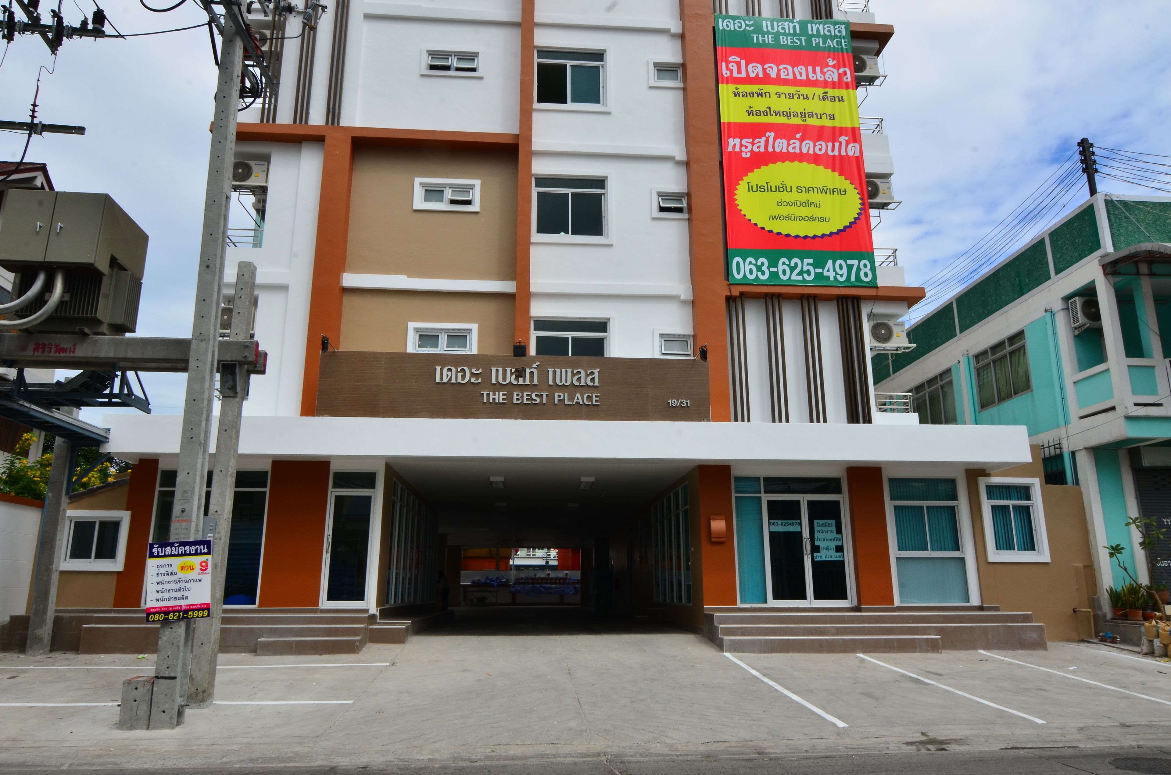 A building with a sign reading "THE BEST PLACE" and a contact number.