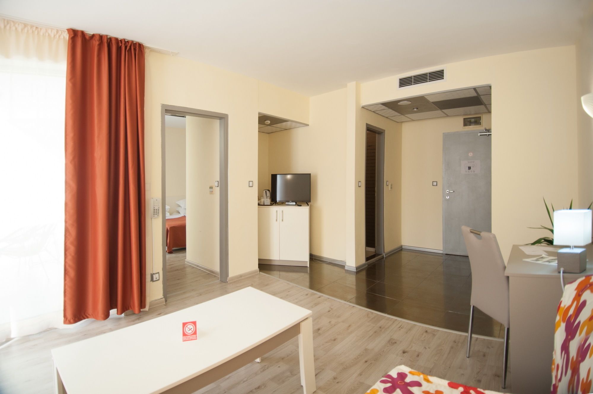 A hotel room with a bed, a TV on a cabinet, a desk, and a chair.