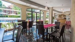 A restaurant with a pool view, modern furniture, and a bar area. - Mariner's Suites (Sunny Beach)