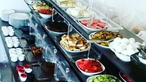 En buffet med forskellige retter og tilbehør anrettet på bakker.