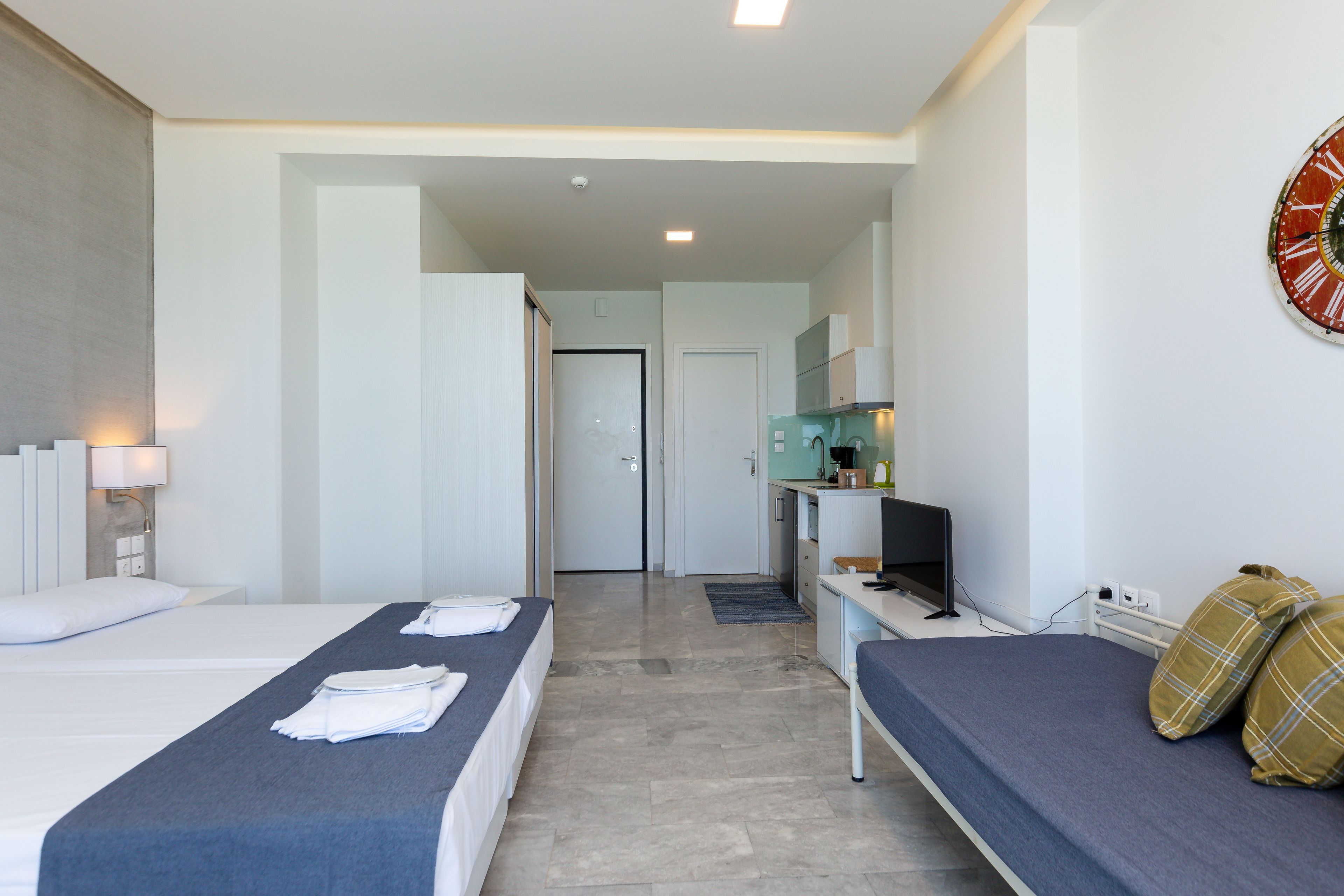 Une chambre d’hôtel avec deux lits, un bureau, une télévision et une salle de bain visible au fond.